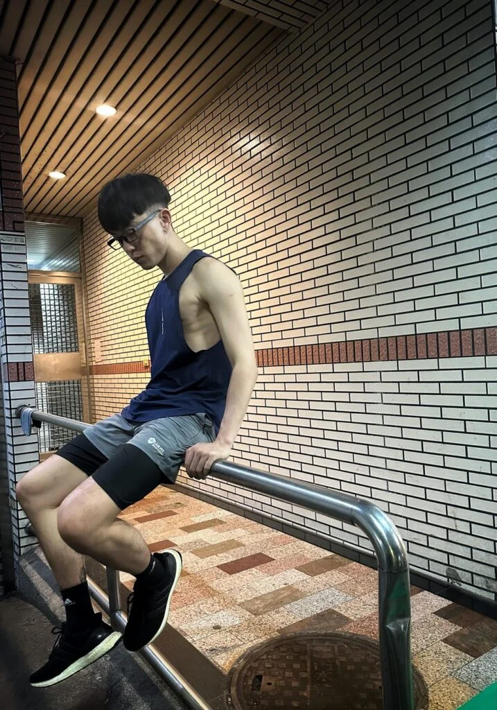 大側開健身背心深藍色 自家實拍 夜晚騎樓坐在欄杆上側身低頭 側腰線清楚