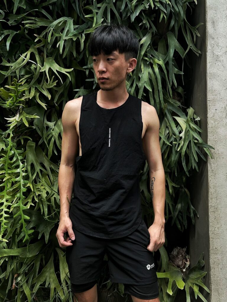 大側開健身背心黑色 自家實拍 白天植生牆前正面站姿雙手插口袋