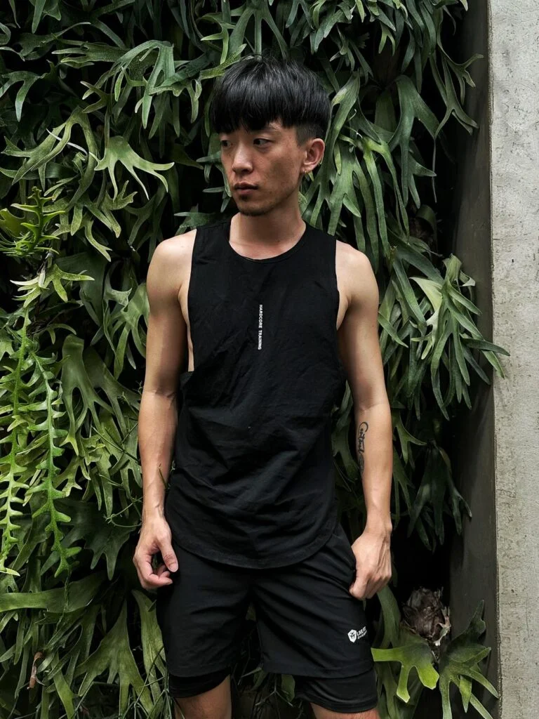 大側開健身背心黑色 自家實拍 白天植生牆前正面站姿雙手插口袋
