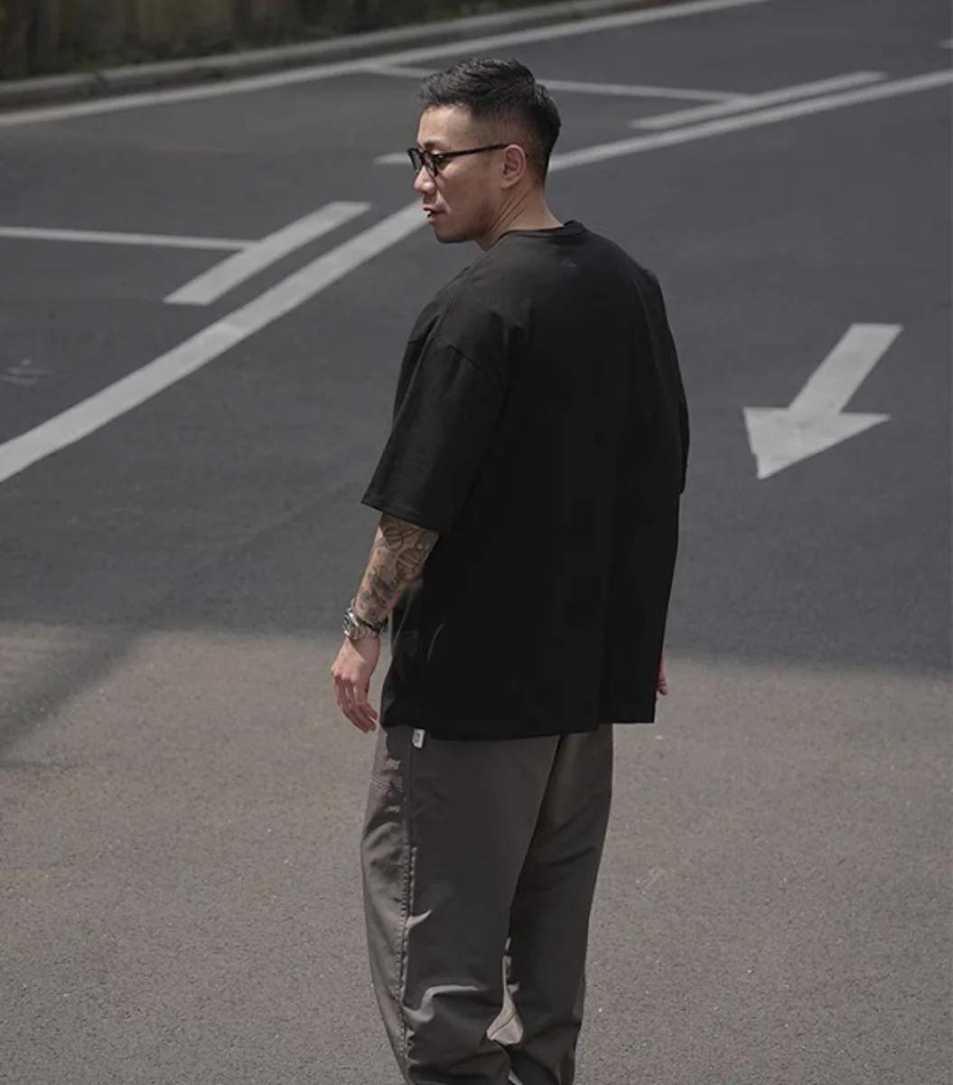 黑色長絨棉柔軟口袋素T側後方穿搭，戶外停車場